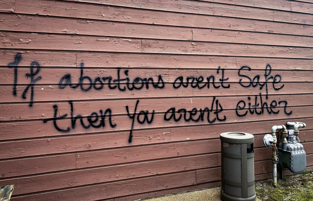 Threatening graffiti is seen on the exterior of Wisconsin Family Action offices in Madison, Wis., on Sunday, May 8, 2022. The Madison headquarters of the anti-abortion group was vandalized late Saturday or early Sunday, according to an official with the group. (Alex Shur/Wisconsin State Journal via AP)